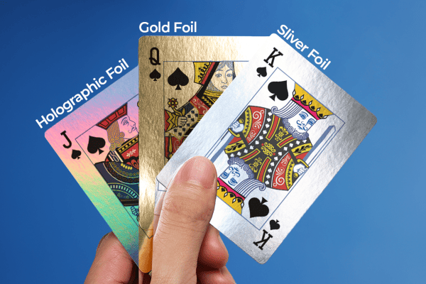hand holding three playing cards show casing different finishes