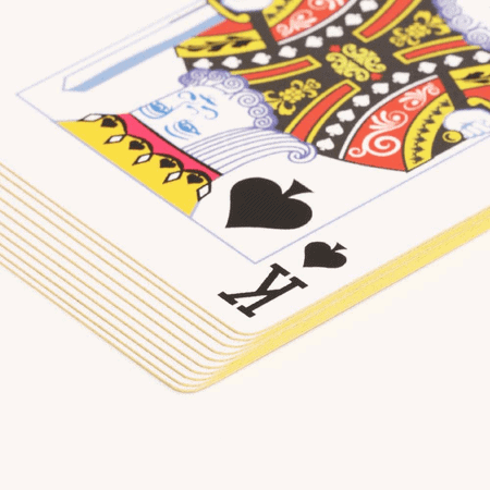 stack of playing cards with gold edges and the king of spades on top