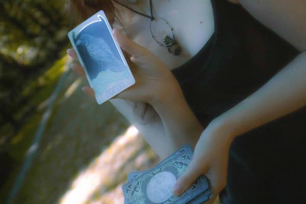 women holding up an oracle card in one hand and the deck of oracle cards in the other