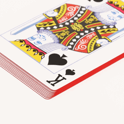 stack of playing cards with red edges and the king of spades on top