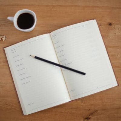 book with pencil on a tabletop with cup of black coffee