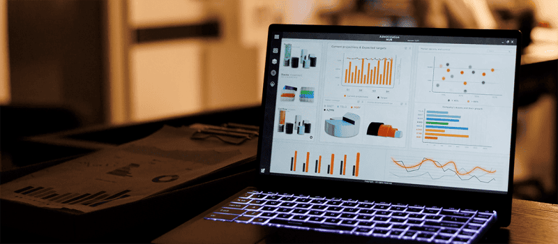 laptop on a desk with a screen filled with charts