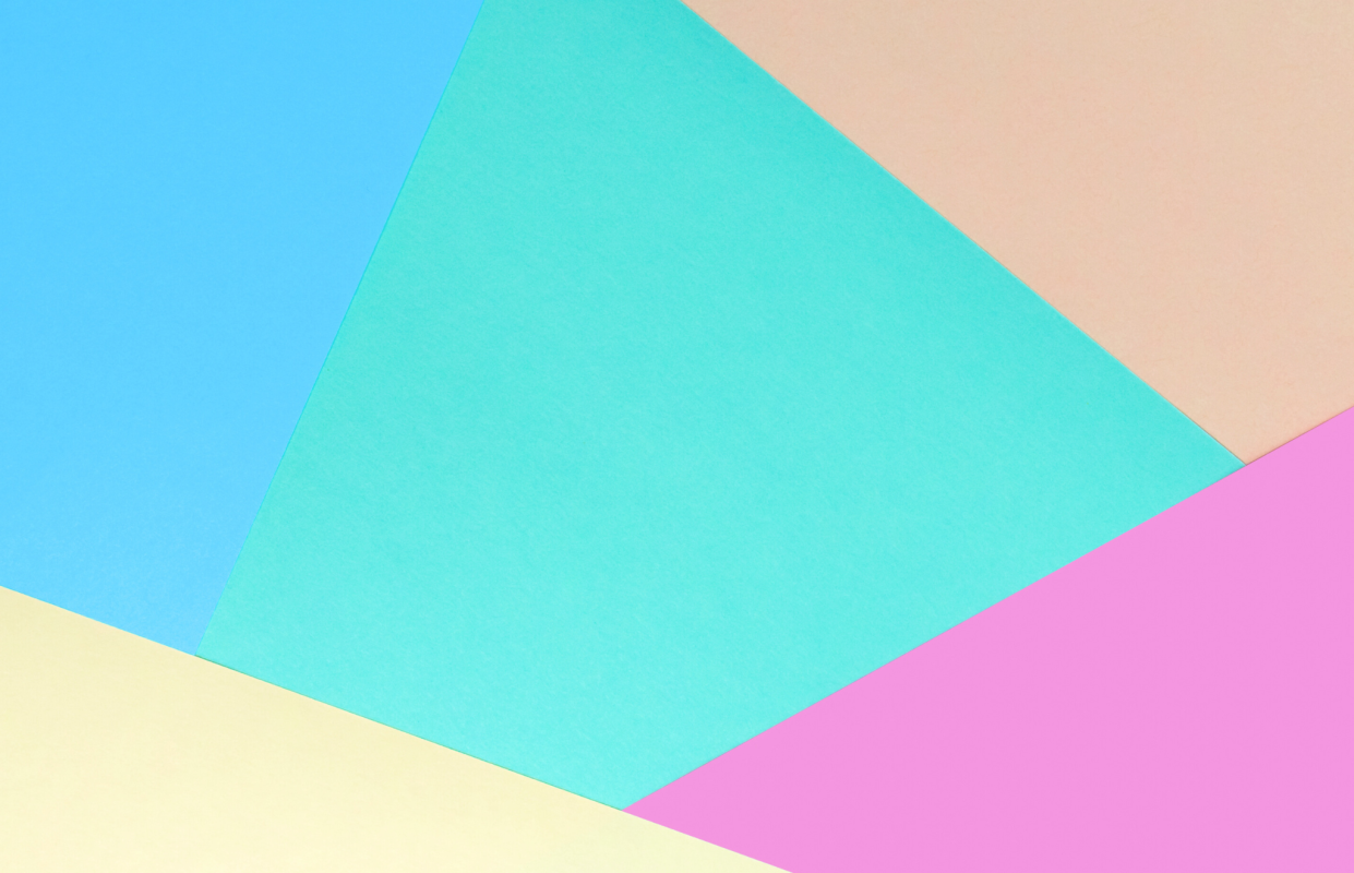 An abstract flat lay image demonstrating the concept of color blocking, with overlapping geometric panels of pastel paper in blue, aqua, pink, and yellow.